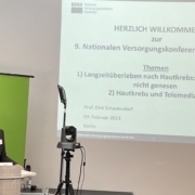 Prof. Dirk Schadendorf steht an einem Redepult und eröffnet die NVKH